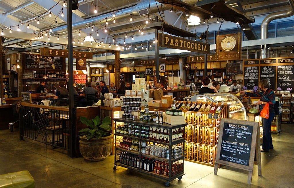 A bustling food market with shelves of products, a café area, and warm lighting.