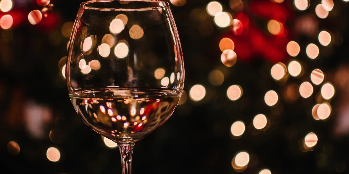 A glass of white wine with blurred festive lights in the background. A glass of white wine with blurred festive lights in the background.