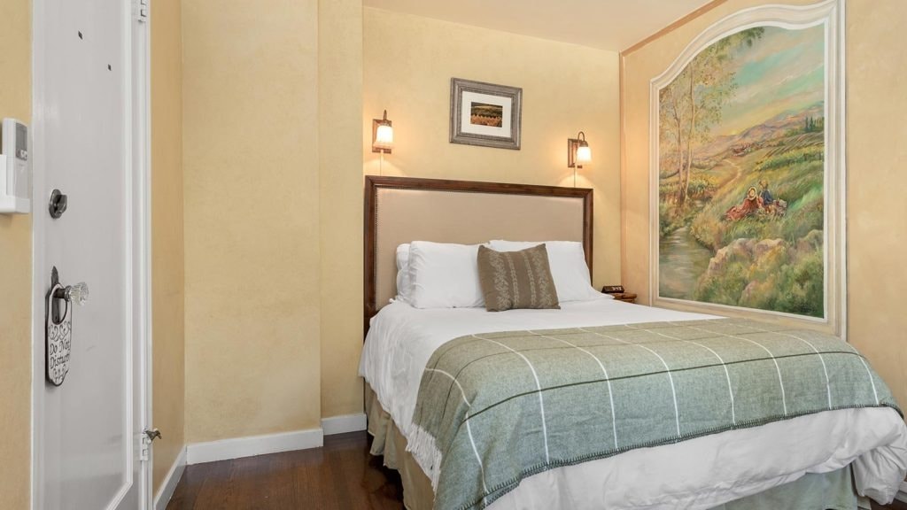Cozy bedroom with a double bed, light-colored walls, and a scenic mural.