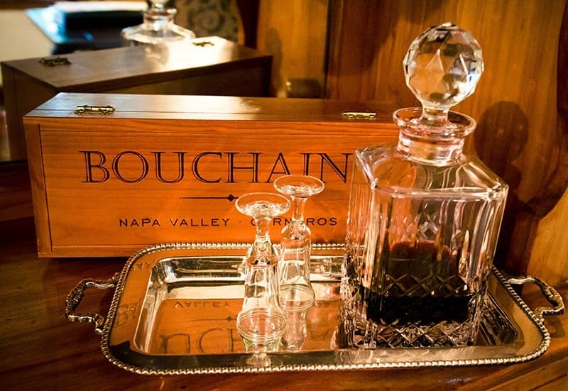 A crystal decanter with glasses on a silver tray next to a wooden wine box labeled "Bouchain, Napa Valley."