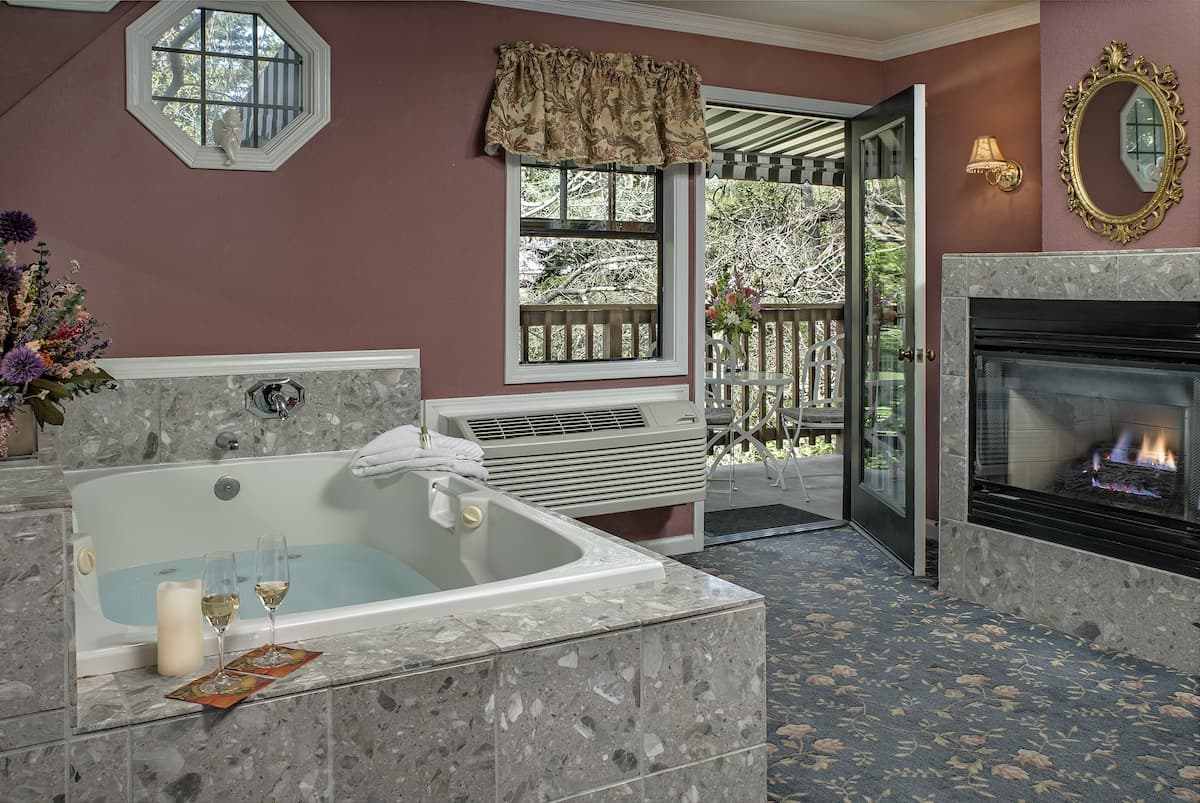A luxurious room featuring a jacuzzi tub, a fireplace, and a cozy outdoor view.