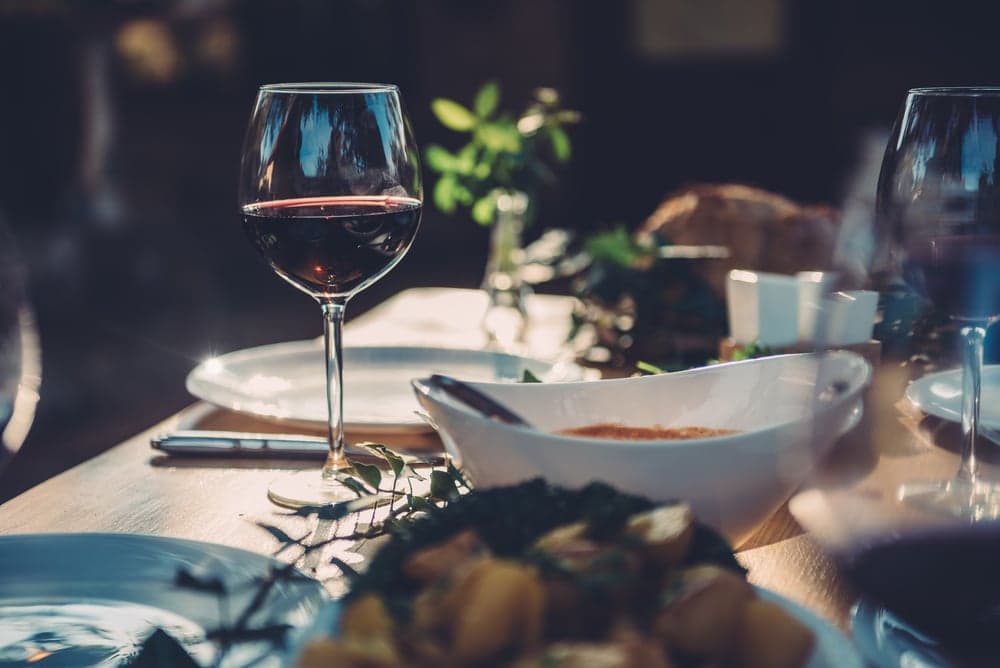 A elegantly set dining table featuring a glass of red wine and various dishes.