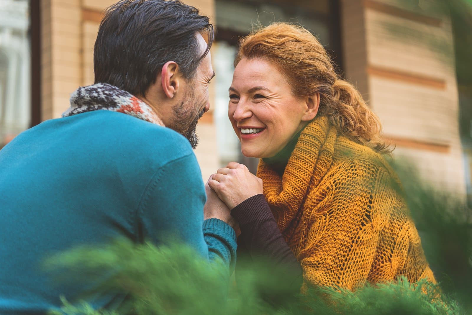 A happy couple engages in a tender moment, smiling and holding hands outdoors.