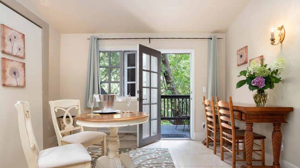 Bright dining area with a round table, chairs, and an open door leading to a balcony.