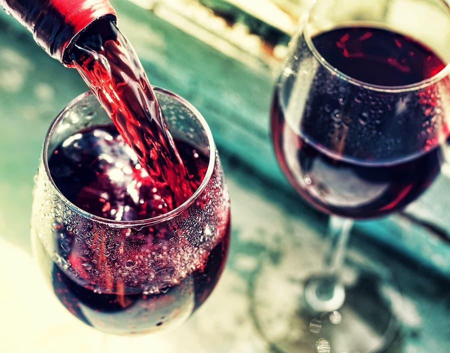Red wine being poured into a glass, with condensation visible on the surface.