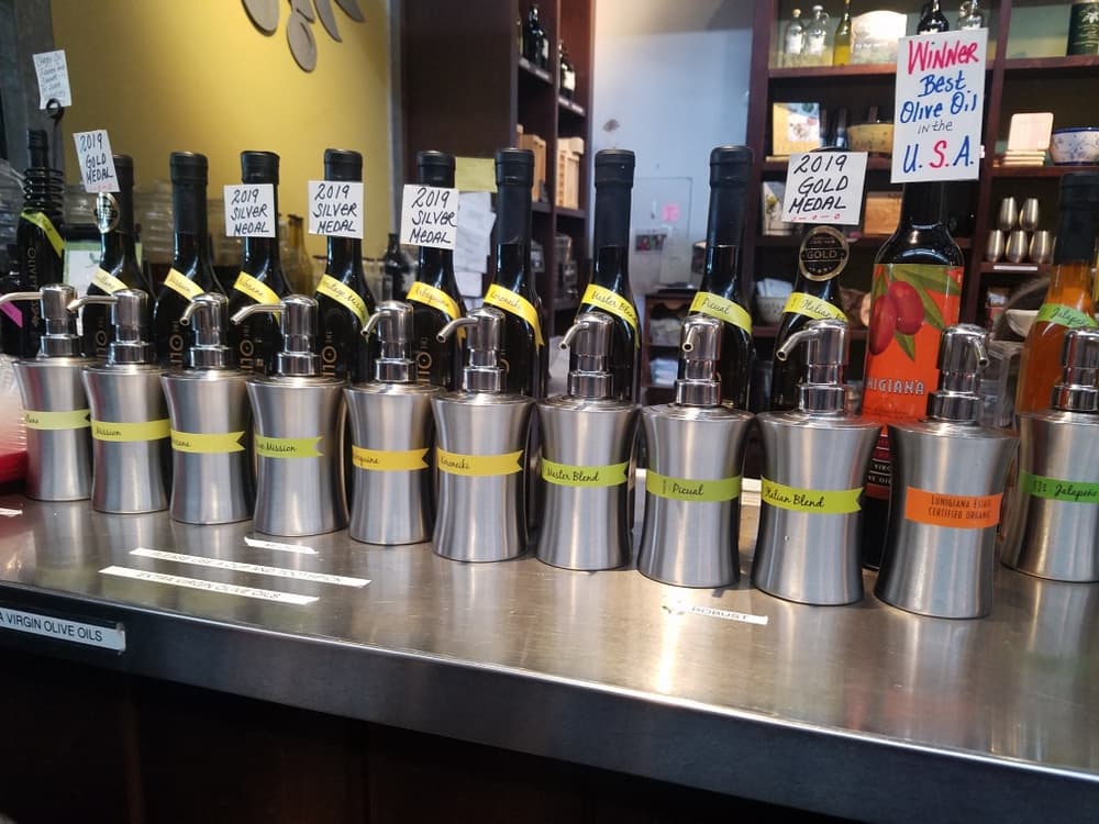 A display of olive oil bottles and tasting containers, showcasing various awards and labels.