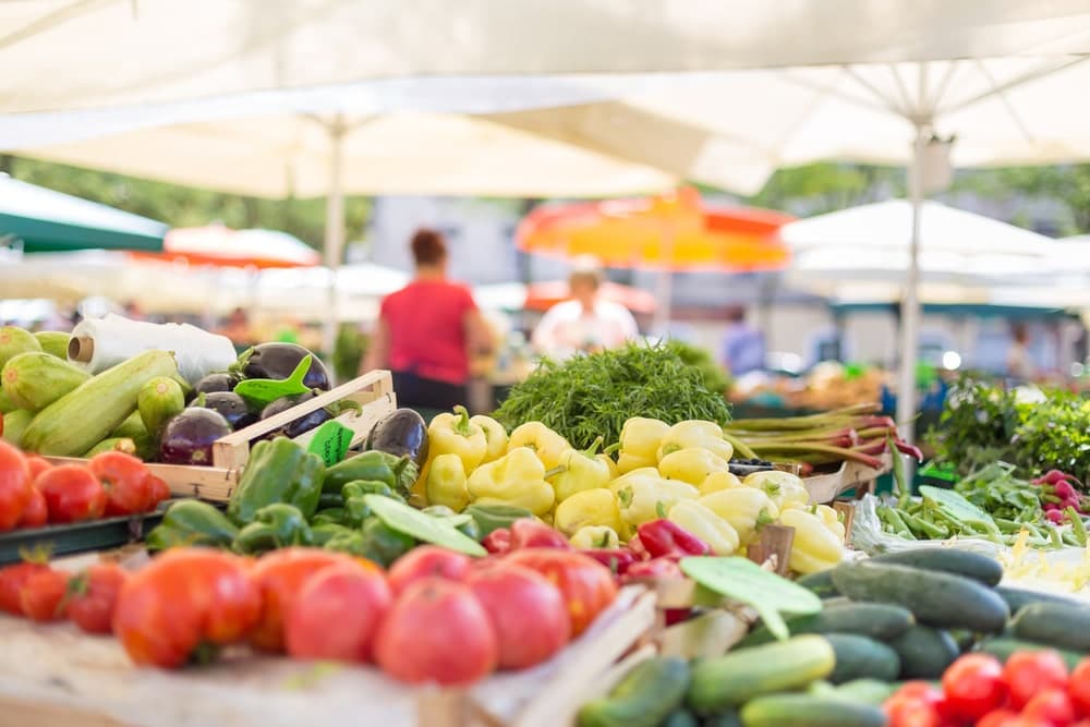 A vibrant farmers' market display filled with various fresh fruits and vegetables under umbrellas.