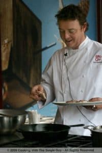 A chef in a white coat prepares food in a kitchen setting.