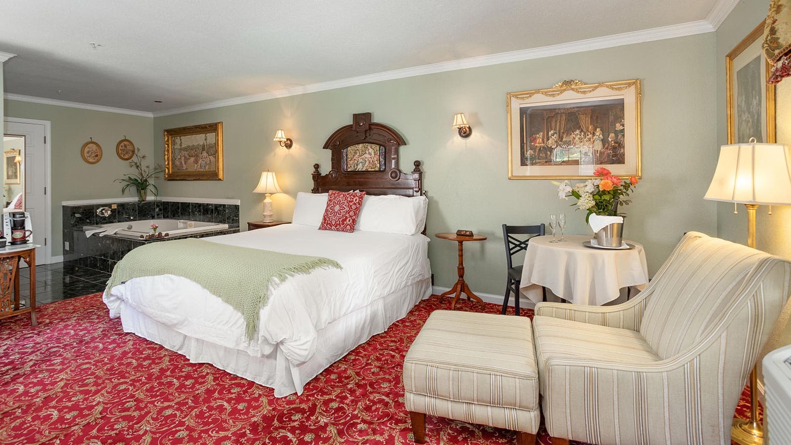 A cozy bedroom featuring a queen bed, elegant decor, seating area, and a decorative carpet.