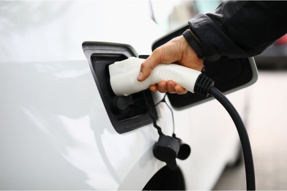 A person plugs an electric vehicle charger into a car.