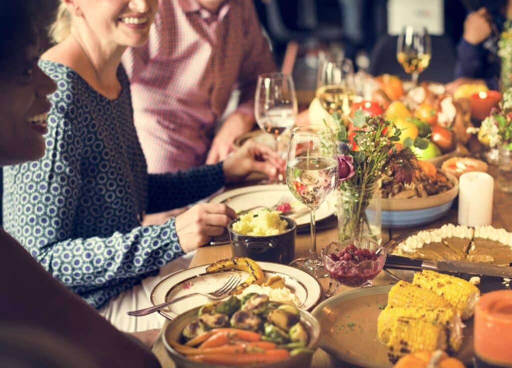 A lively dinner table spread with various dishes, drinks, and people enjoying each other's company.