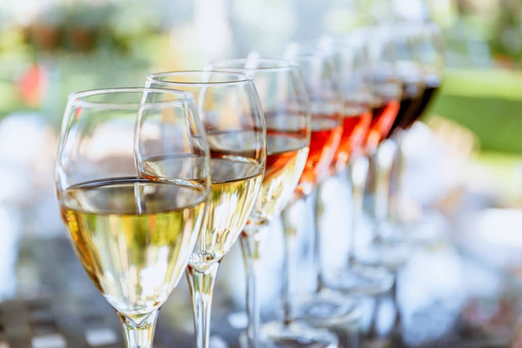 A row of wine glasses filled with different types of wine.