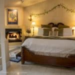A cozy bedroom featuring a large bed, decorative pillows, and a fireplace.