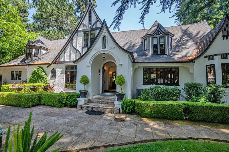 A charming Tudor-style house with manicured gardens and lush greenery.