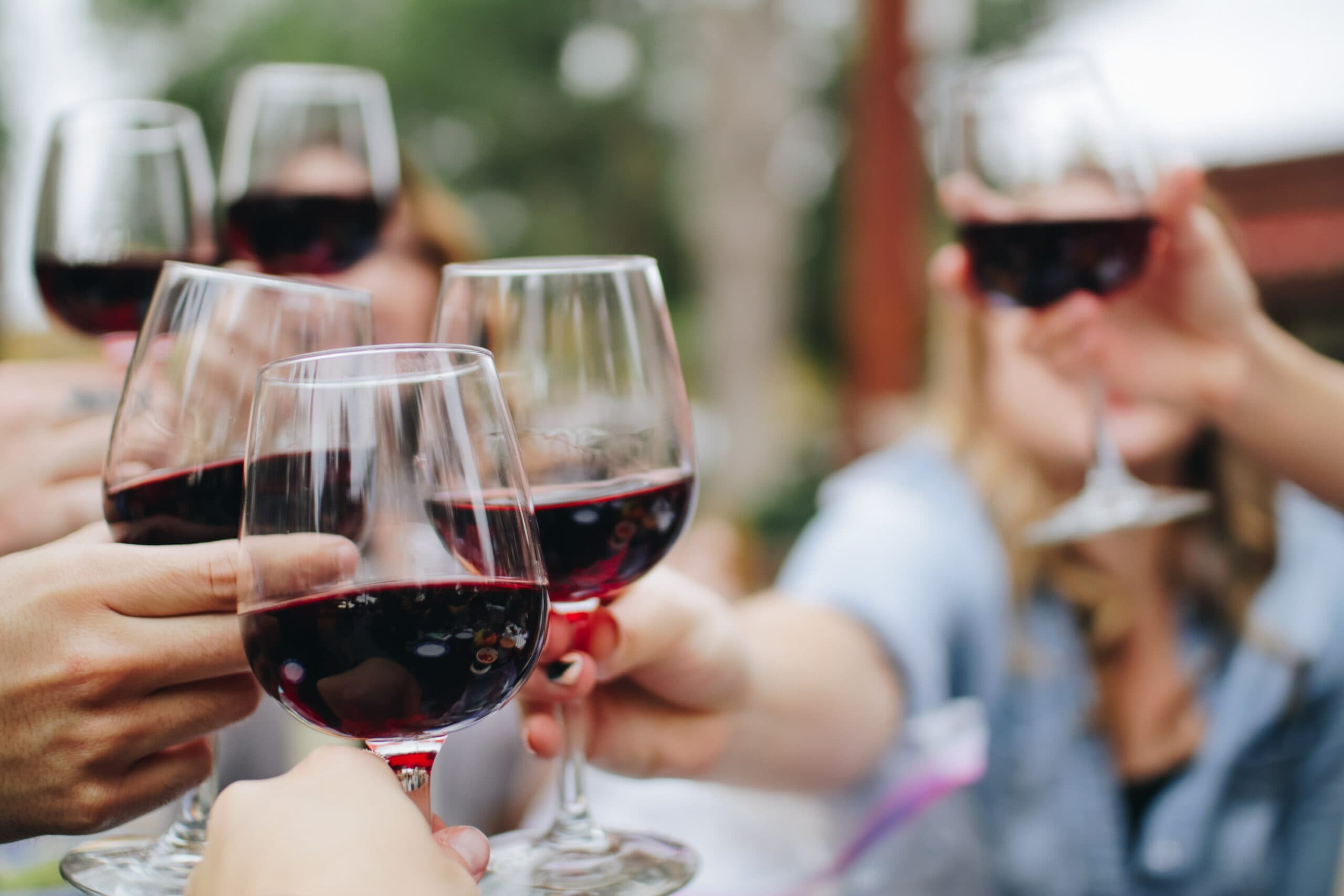 A group of people raising glasses of red wine in a celebratory toast.